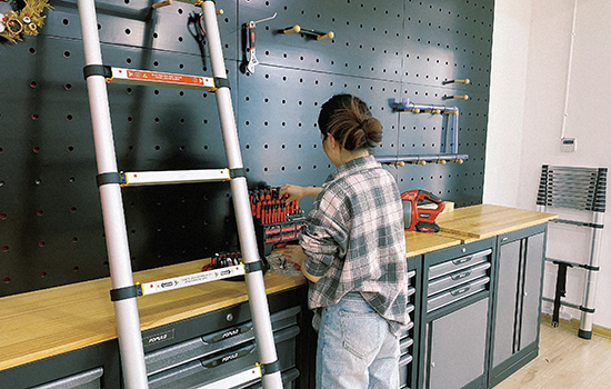 Una niña está clasificando sus herramientas de hardware con una escalera telescópica de cierre suave